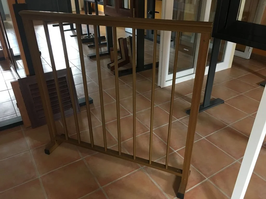 Reja de madera para bebés en el interior de un establecimiento con suelos de cerámica y otras rejas y ventanas.
