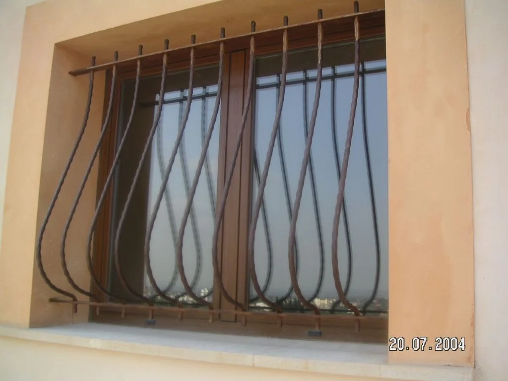 Reja de seguridad de barrotes de metal en la ventana, con ventanas de madera y cristales.