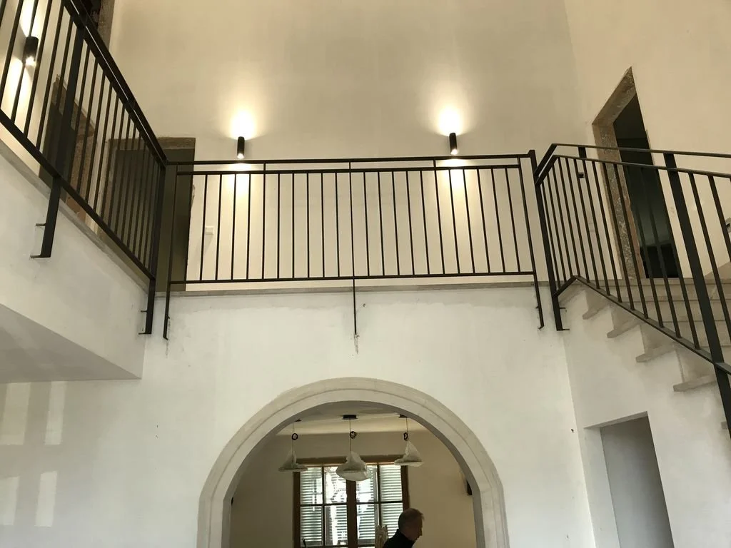 Interiores de una casa con un patio interior y una escalera de metal negra.