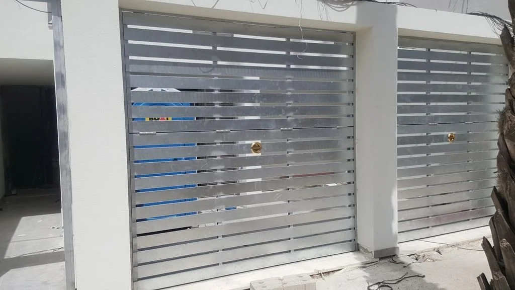 Puertas metálicas correderas blancas en una entrada de residencia moderna.