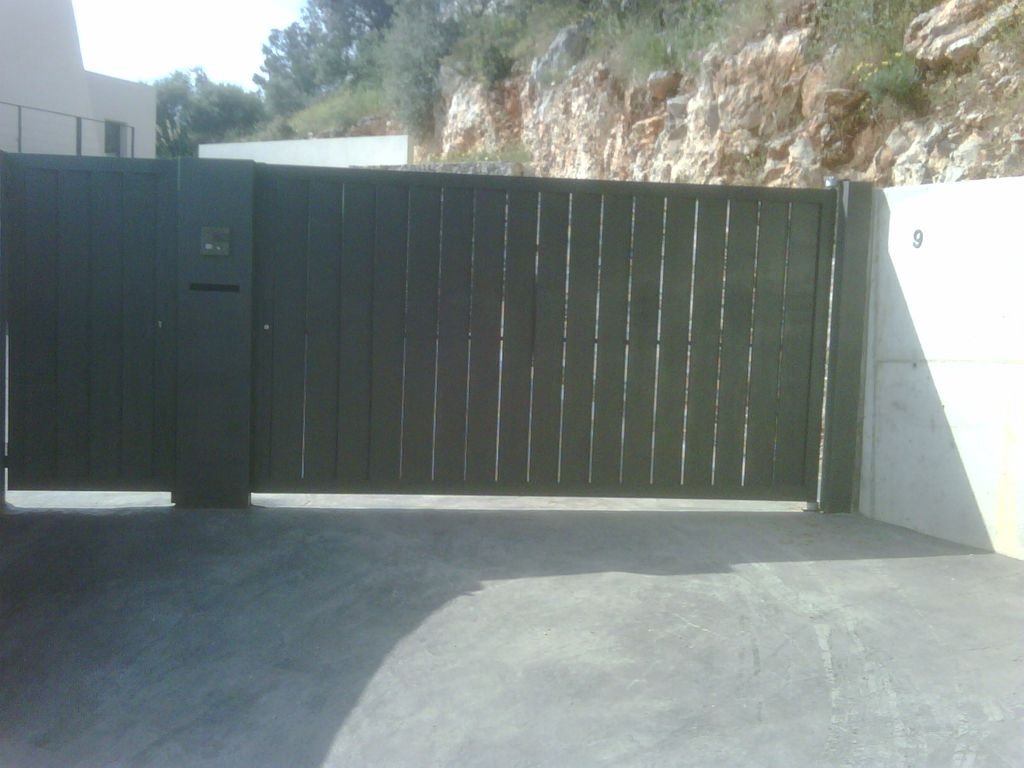 Reja de puerta negra en entrada de propiedad con muro de concreto y señal de número 9