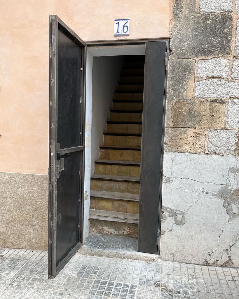 Puerta abierta que muestra unas escaleras internas con el número 16 en la parte superior.