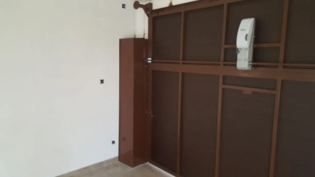 Vista de una pared blanca con una estructura enmarcada de madera para un clóset o armario, y un proyector montado en la estructura.