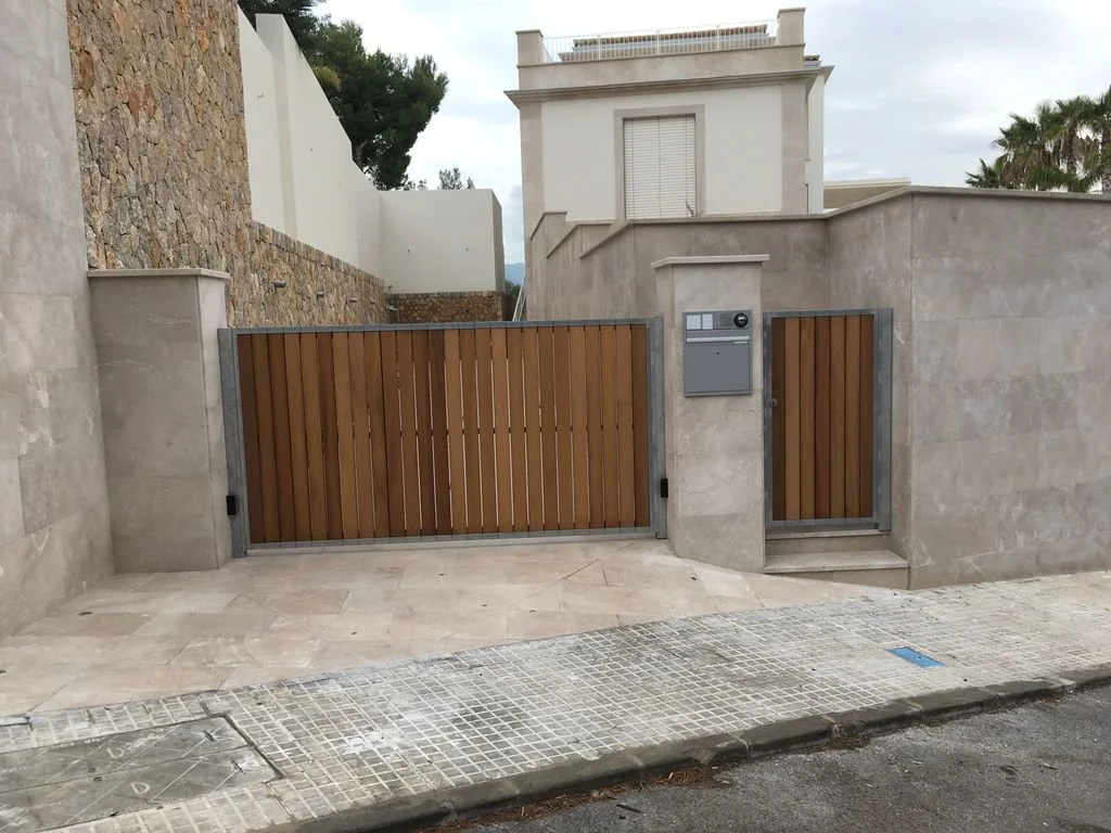 Puerta de entrada de madera con muro de piedra y muro de cemento en una casa moderna.