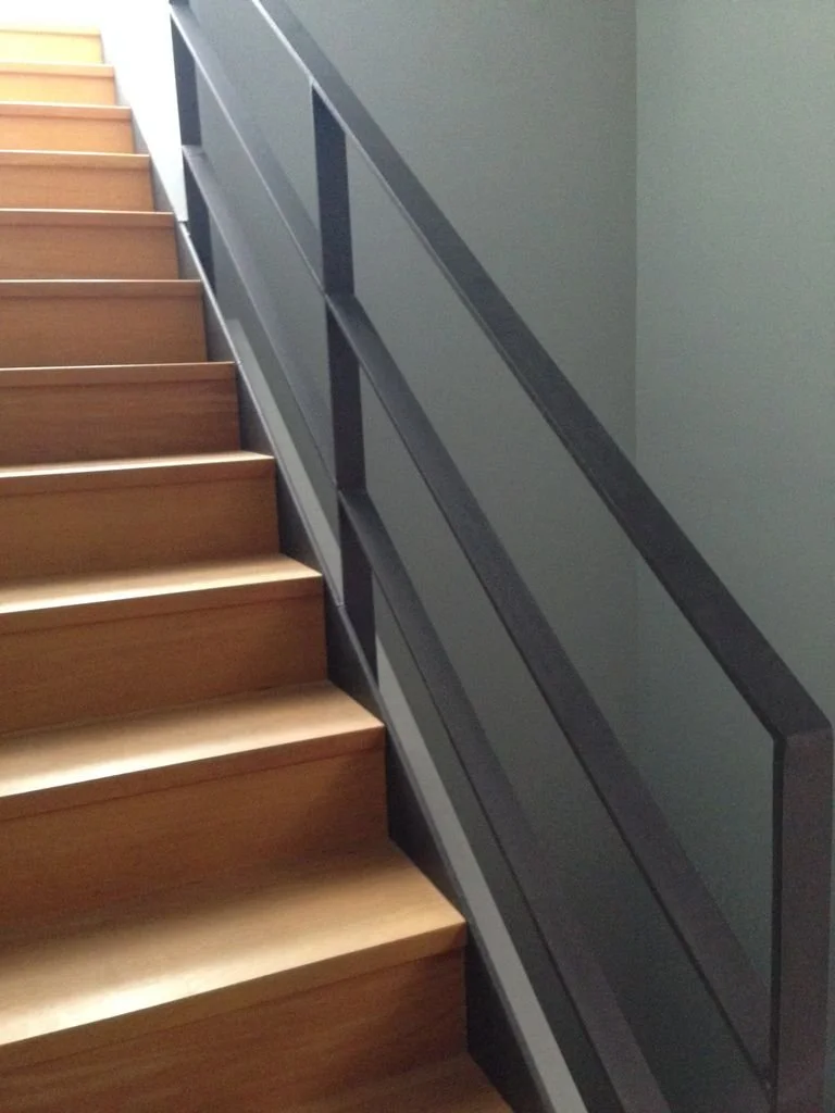 Escalera de madera con barandal metálico en interior.