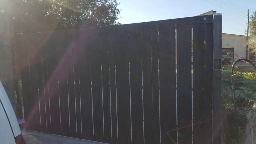 Puerta corredera de madera pintada de negro en un entorno exterior.