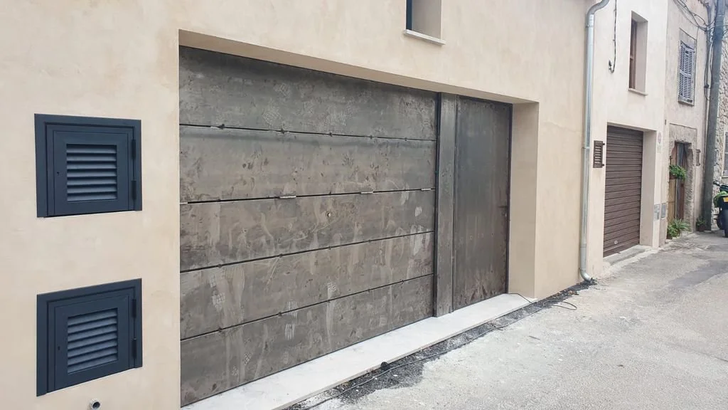 Puerta de garaje de madera marrón y pared de edificio en calle.