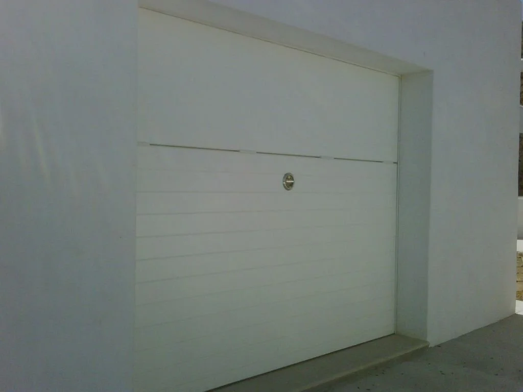 Puerta de garaje blanca moderna en una estructura de paredes blancas.