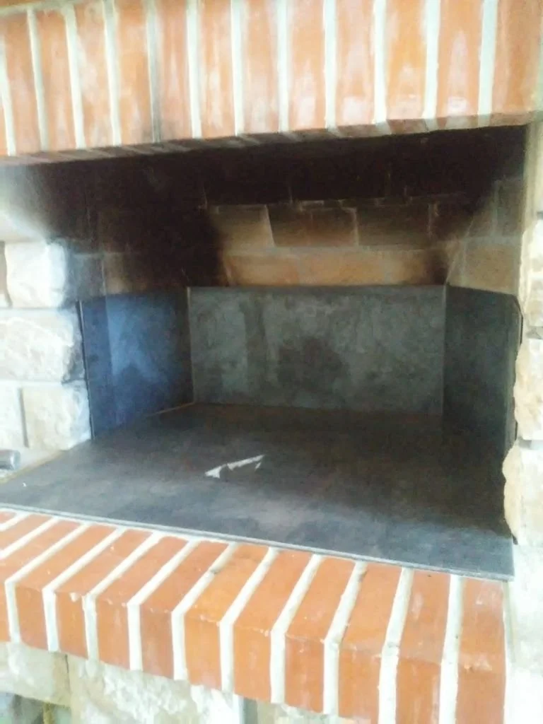 Fuego abierto de una chimenea de ladrillo y piedra.