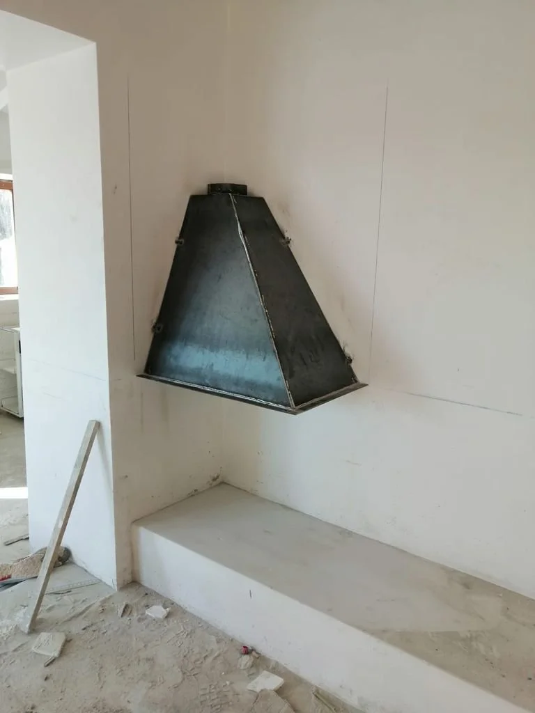Campana extractora de cocina en construcción, instalada en una pared de muro blanco.