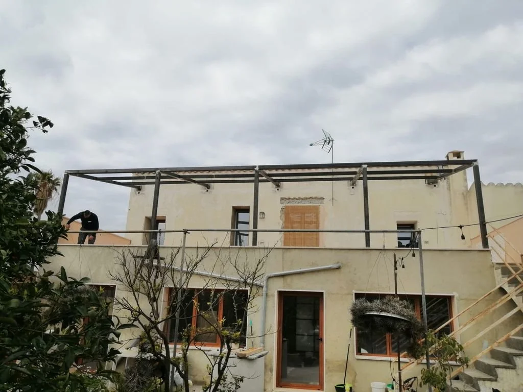 Construcción de una estructura metálica en la azotea de un edificio con ventanas y escaleras exteriores.