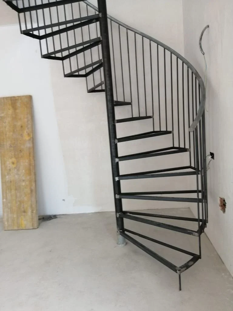 Escalera de espiral de metal en construcción, instalada en una habitación vacía.