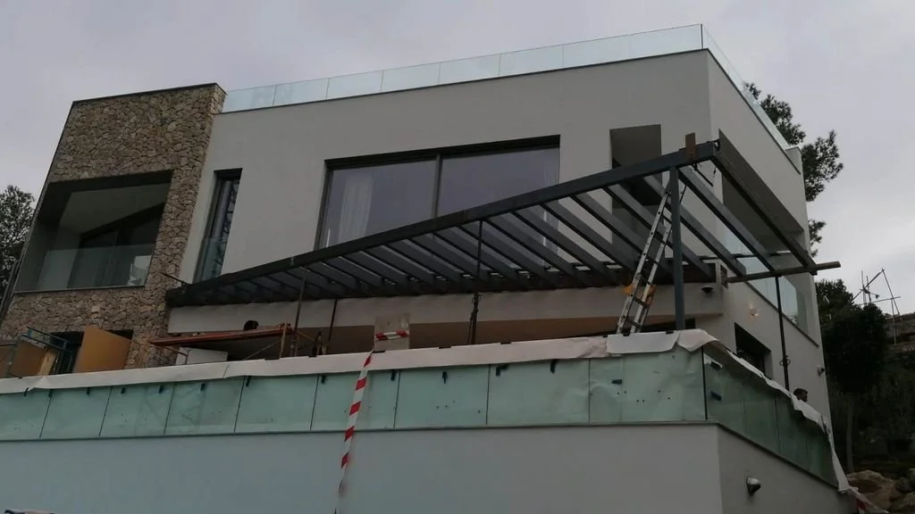 Construcción de una terraza en un edificio moderno, con estructura metálica y escalera, en un día nublado.