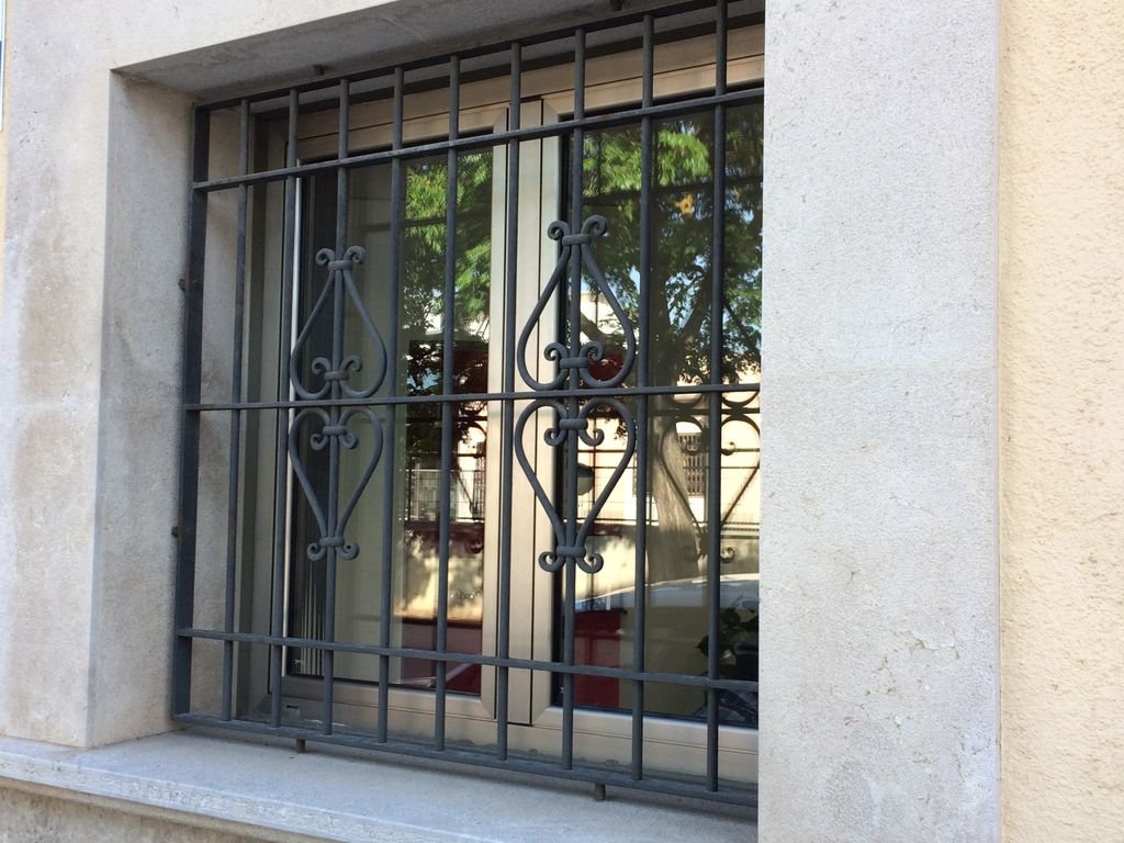 Ventana con reja de barrotes de metal decorativos en una casa.