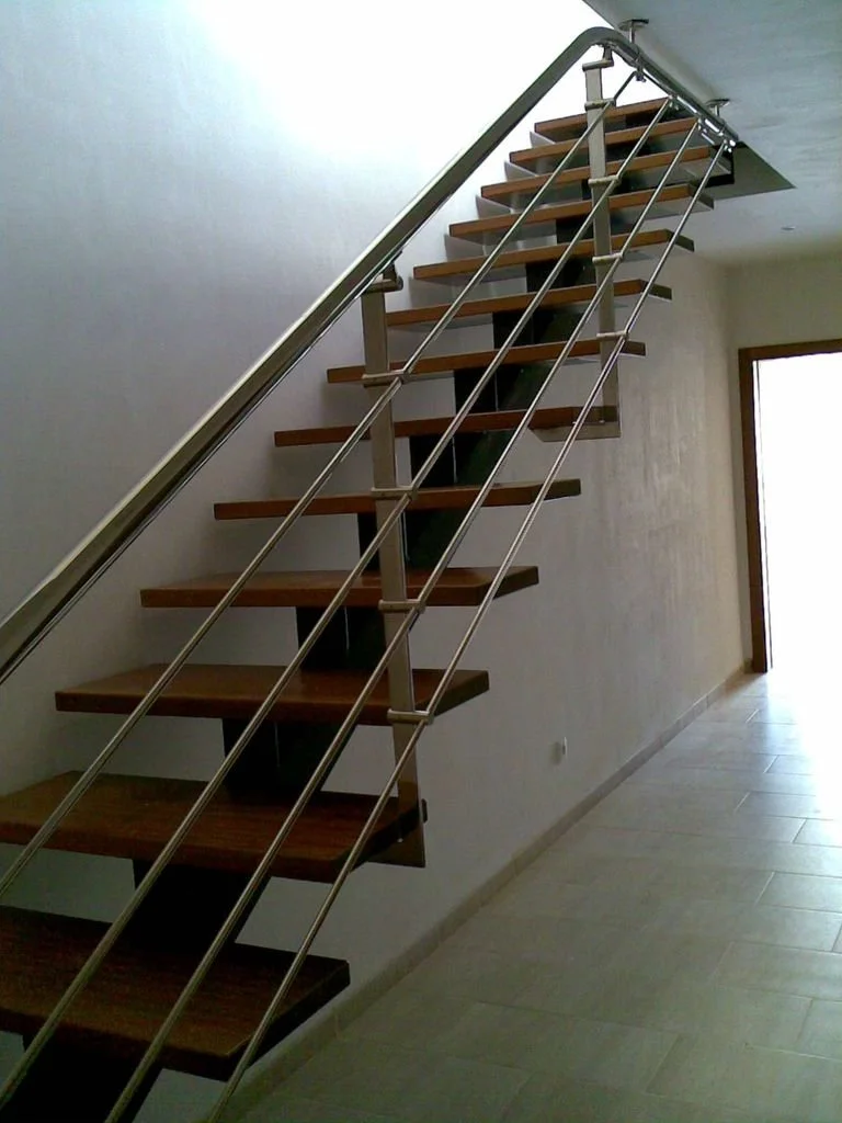 Escalera moderna con peldaños de madera y barandilla de metal en interior de casa.