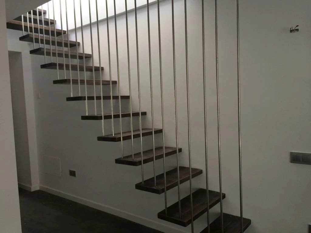 Escalera moderna de madera con barandales de metal en interior de casa