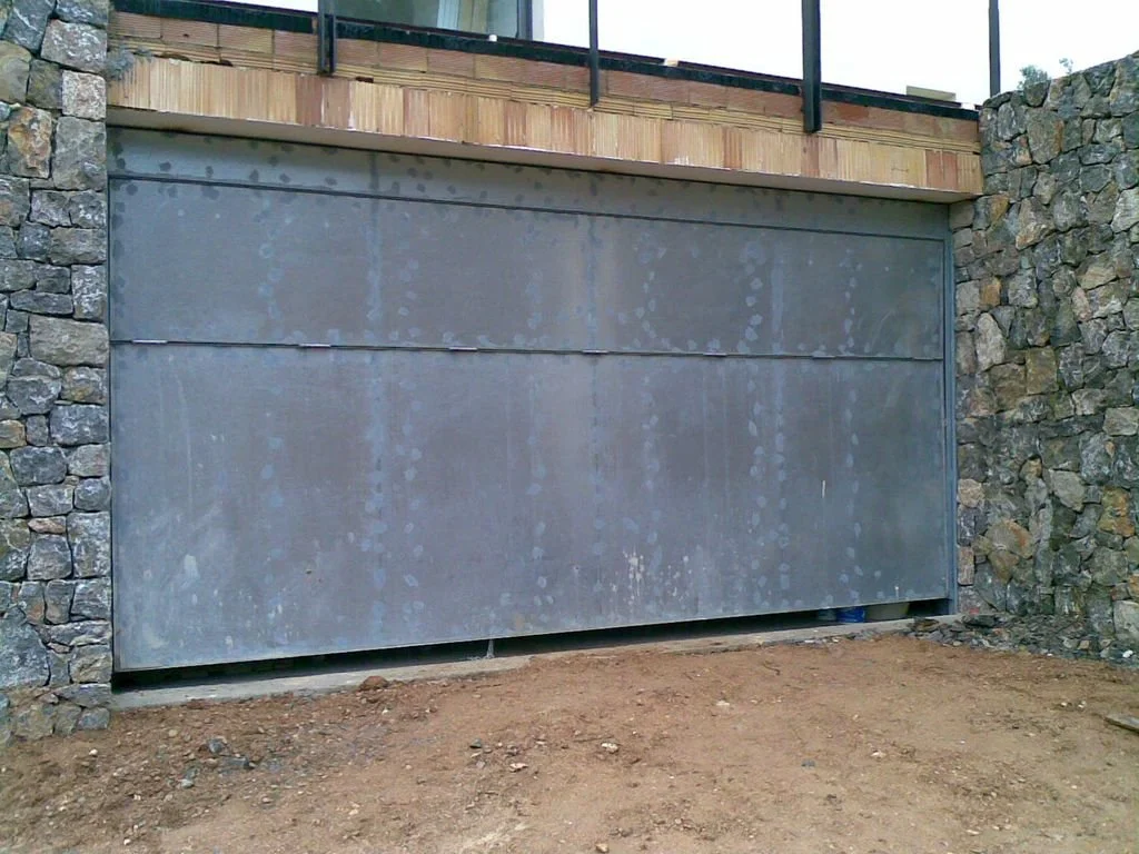 Puerta de garaje metálica en un muro de piedra, en construcción o renovación