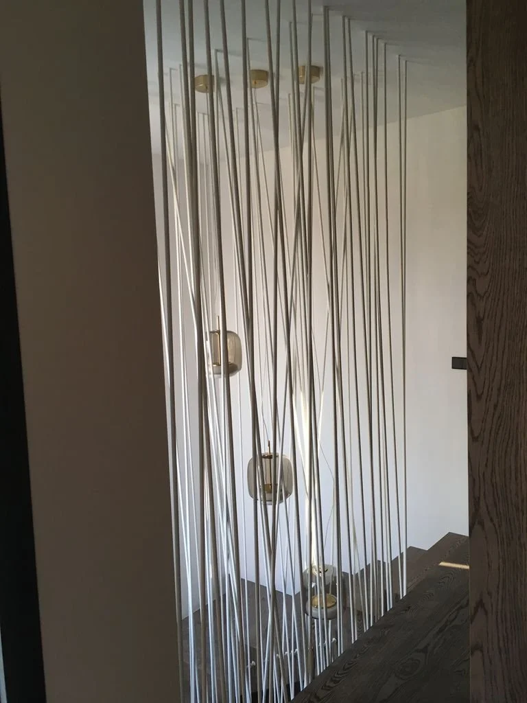 Pantalla decorativa con varillas metálicas delgadas y luminarias en una casa moderna.