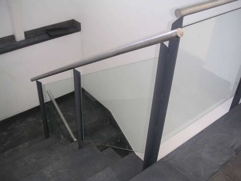 Escalera interna con barandal de metal y paredes blancas en un edificio.