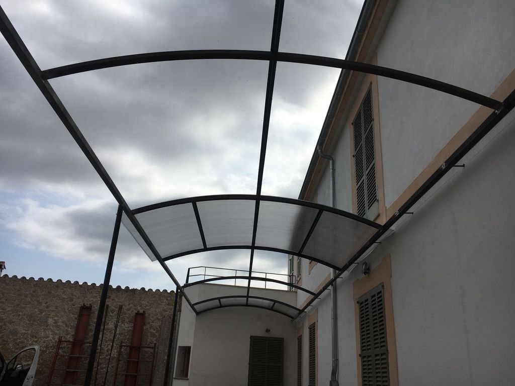 Estructura de cobertizo o techado con cristales en un patio trasero de una casa.