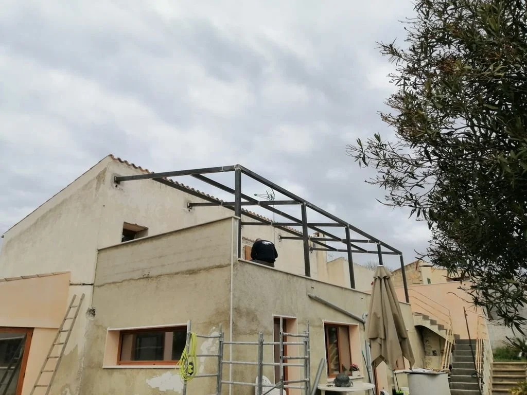 Construcción en proceso en una casa de dos pisos con estructura metálica en el patio