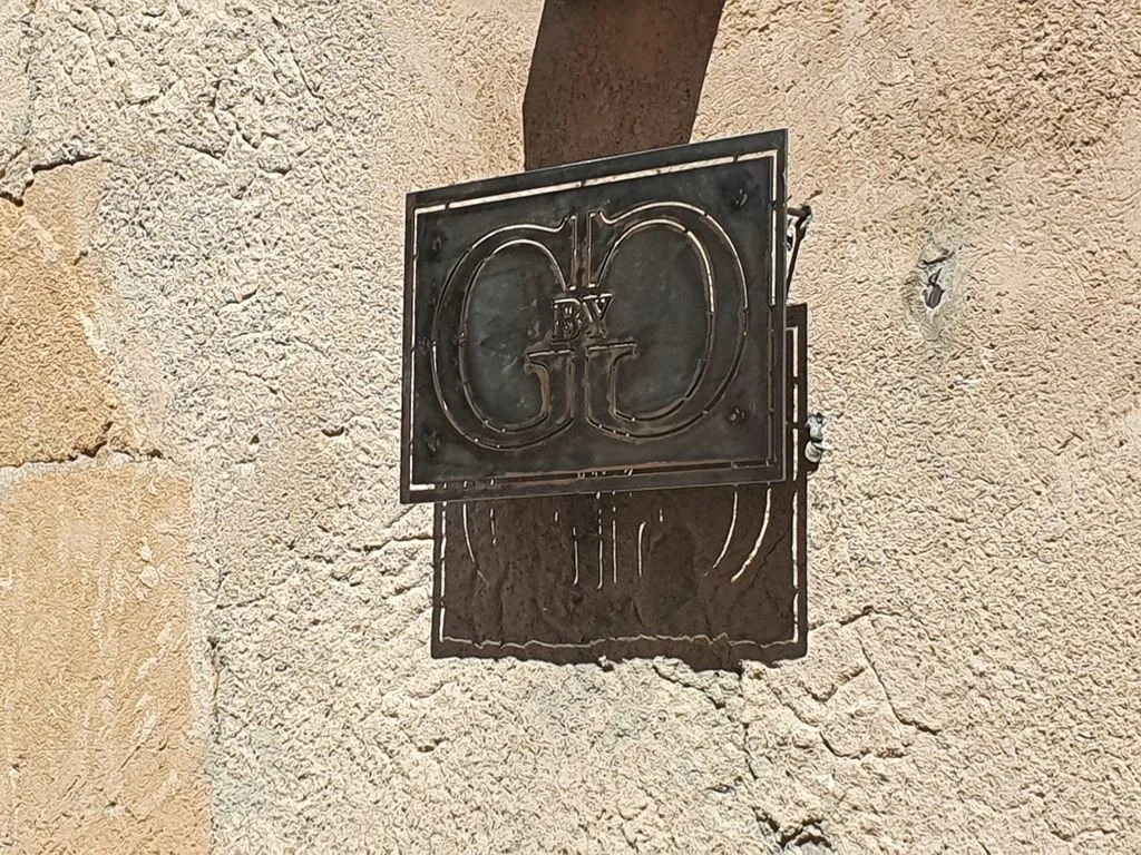 Un cartel de metal en la pared de una piedra con las letras 'GO' y una marca adicional en medio.