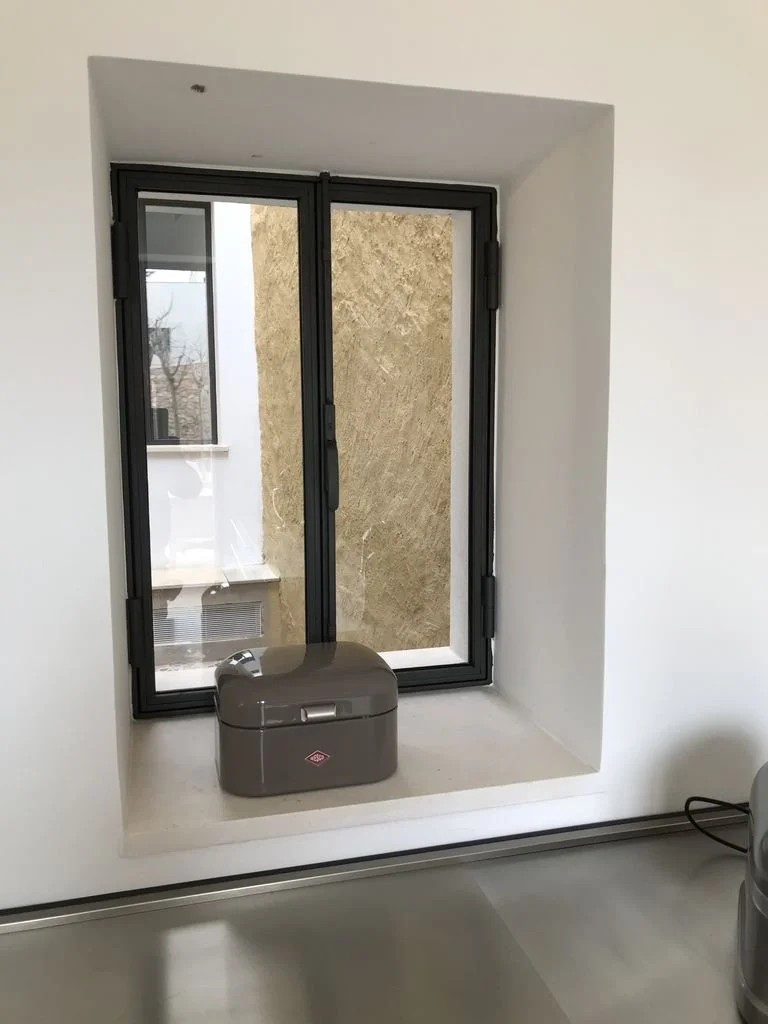 Ventana de doble acristalamiento con marco negro y una caja gris en el alféizar