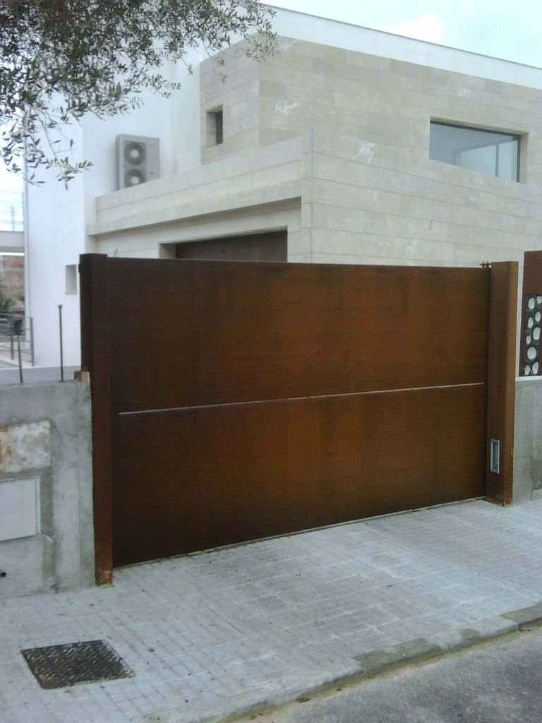 Puerta de entrada de color marrón en la cerca de una casa moderna de bloques claros