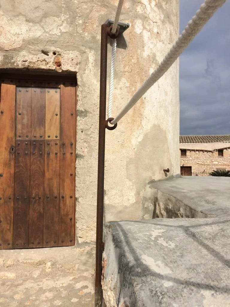 Cuerda y barandilla de seguridad junto a una pared de piedra y una madera estilo rústico.