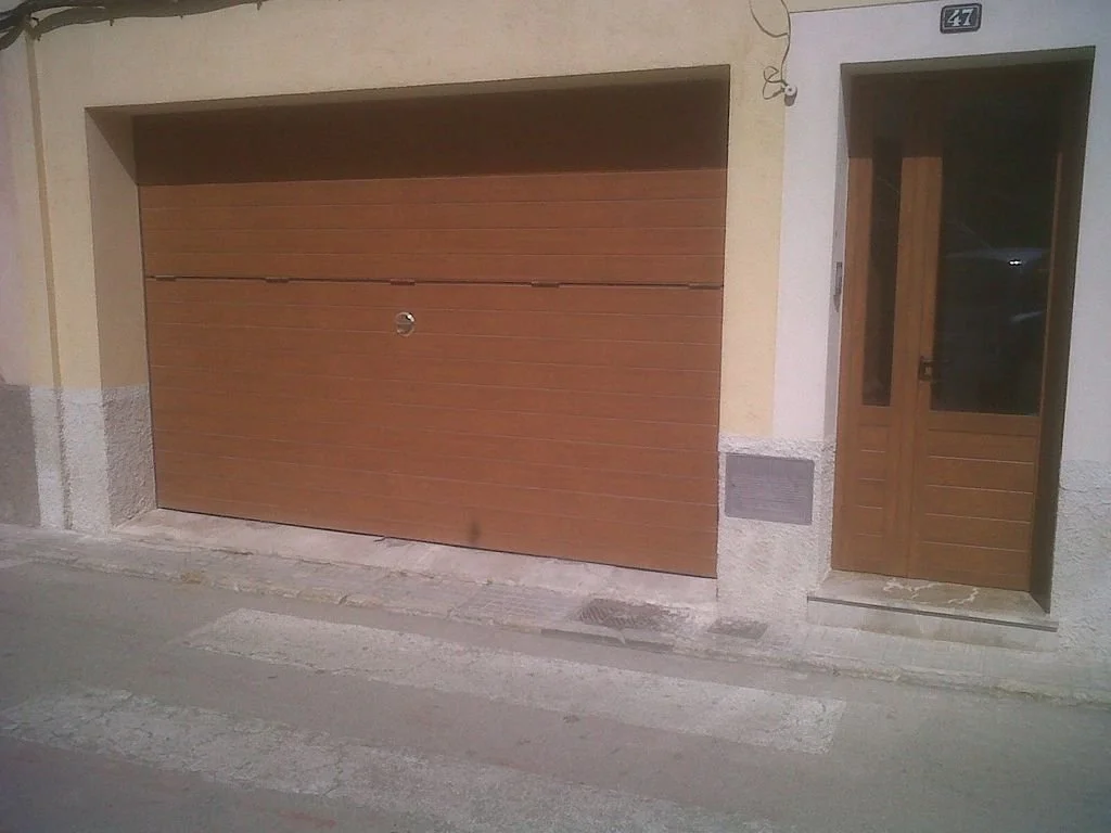 Puerta de garaje de color marrón y entrada peatonal con puerta de madera.