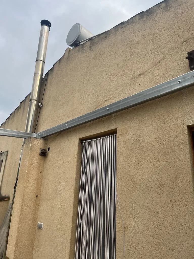 Edificio con ventilación en la azotea, incluyendo un tubo de escape, un altavoz y una estructura metálica en la pared