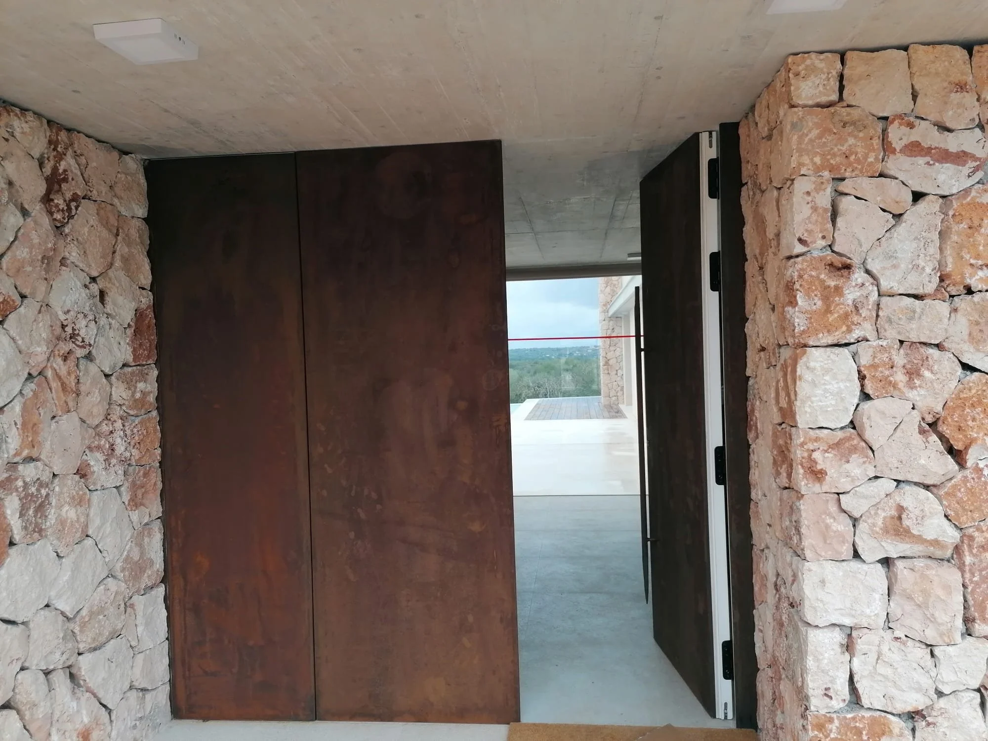 Resumen de la cocina con paredes de piedra, horno de moderno diseño y vista a un balcón con paisaje de naturaleza.