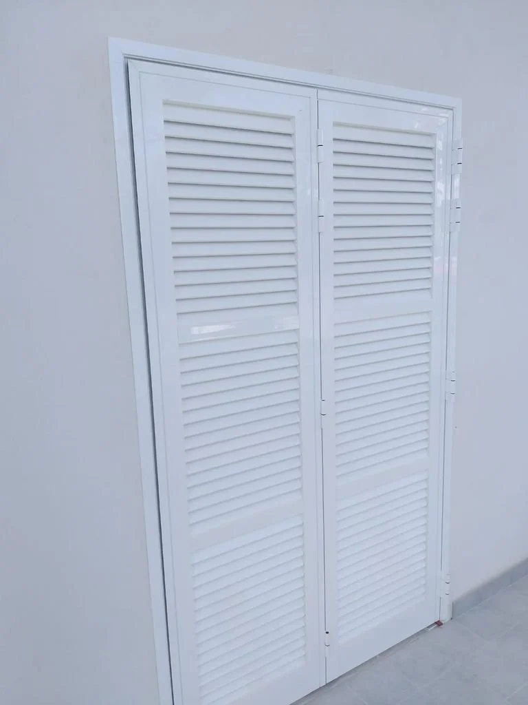 Puertas blancas de lamas en un muro blanco.
