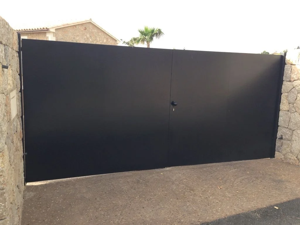 Puerta de garaje negra en un muro de piedra con un candado en el centro.