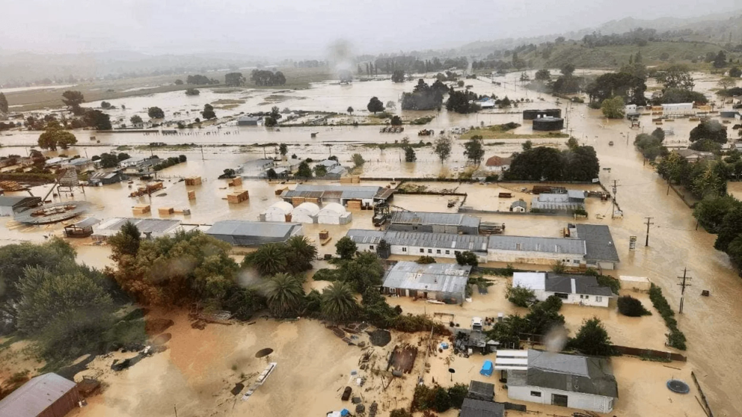 Wairoa flooding residential area with submerged houses, streets, and trees, during a severe flood caused by Cyclone Gabrielle