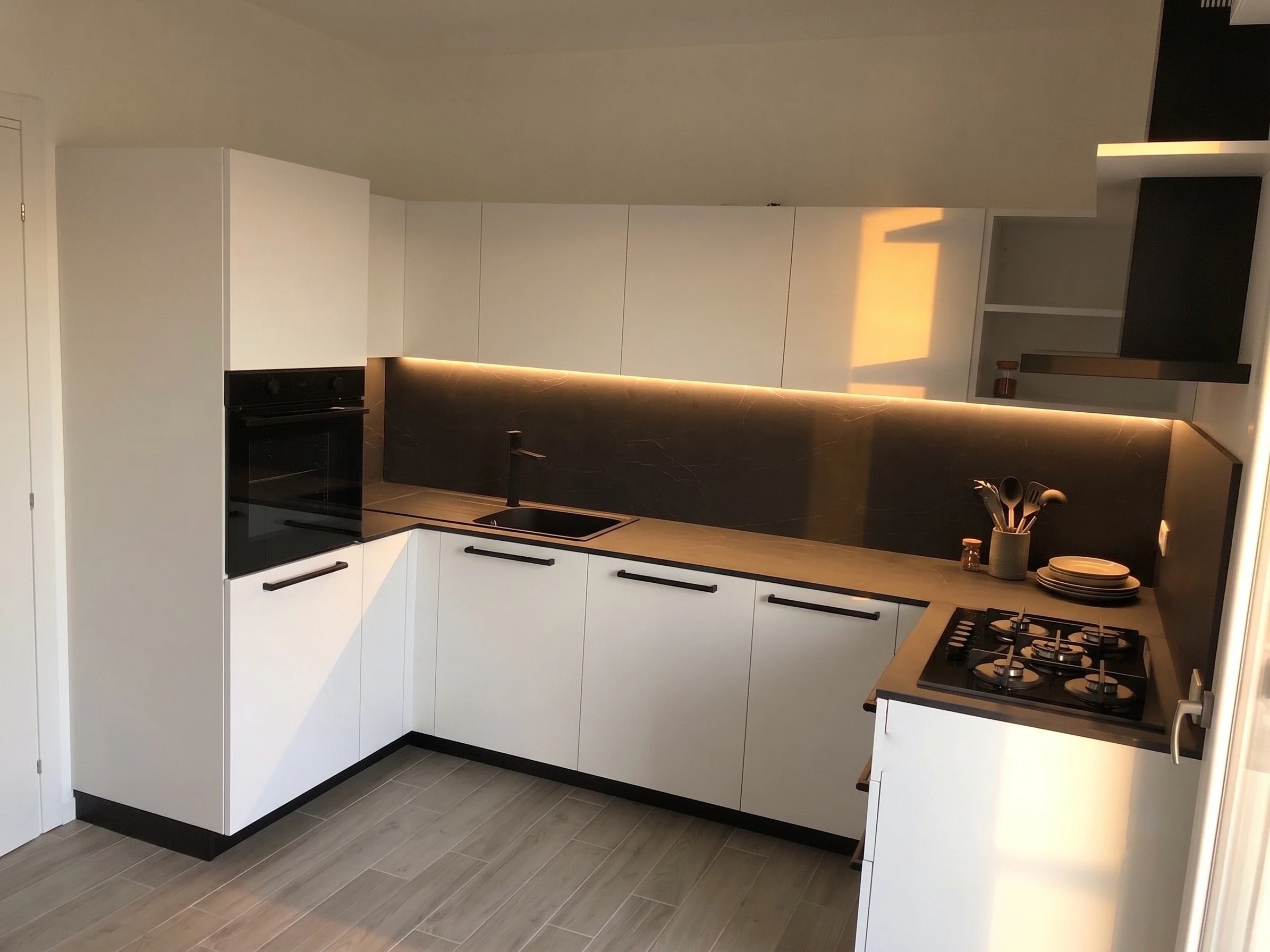 Cucina moderna bianca con piani in marmo nero e piano cottura a gas