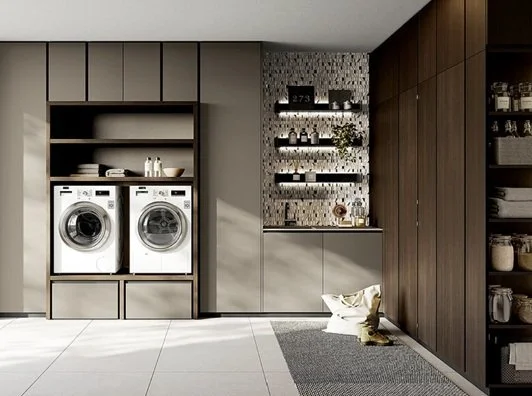 Lavatrici e scaffali in una lavanderia moderna con pareti beige e armadi scuri.