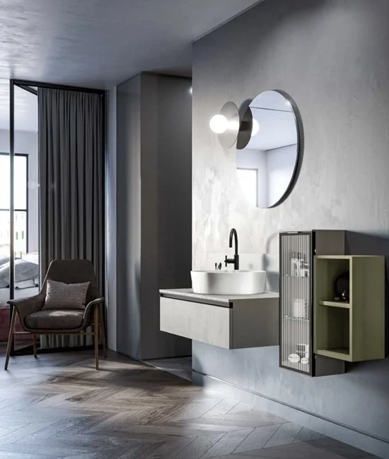 Interni moderni con lavabo bianco, specchio rotondo, sedia con rivestimento in tessuto e finestra con tende grigie.