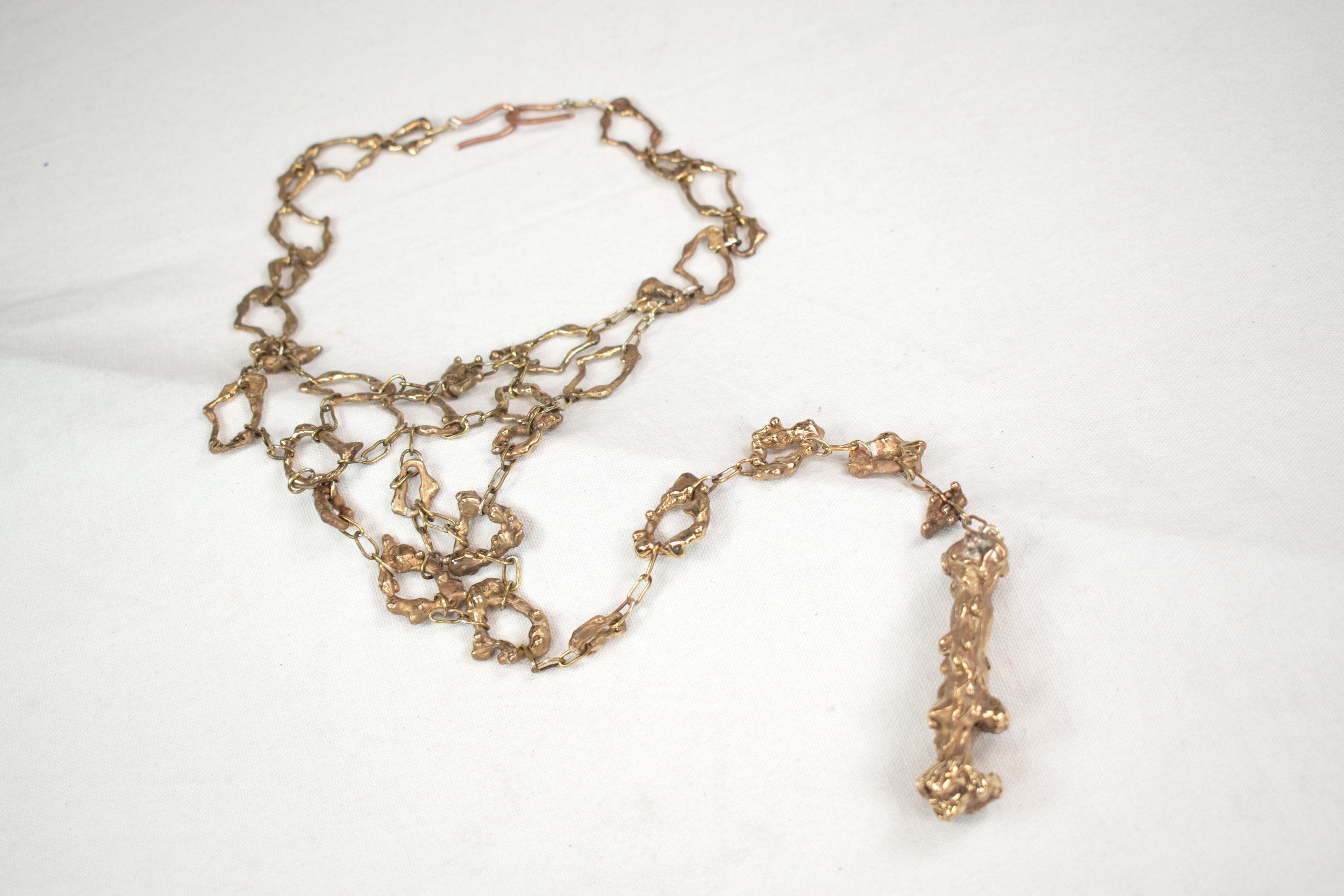 Gold chain jewelry displayed on a white fabric surface.