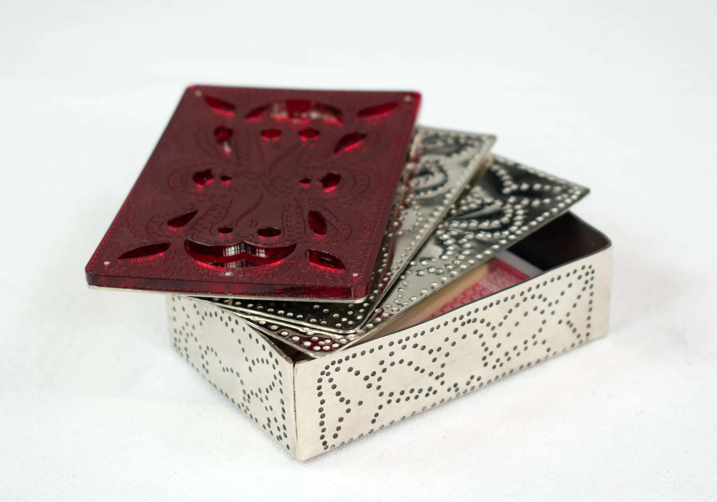 A stack of playing cards with a red card on top featuring a decorative eagle design, placed on a dotted white box.