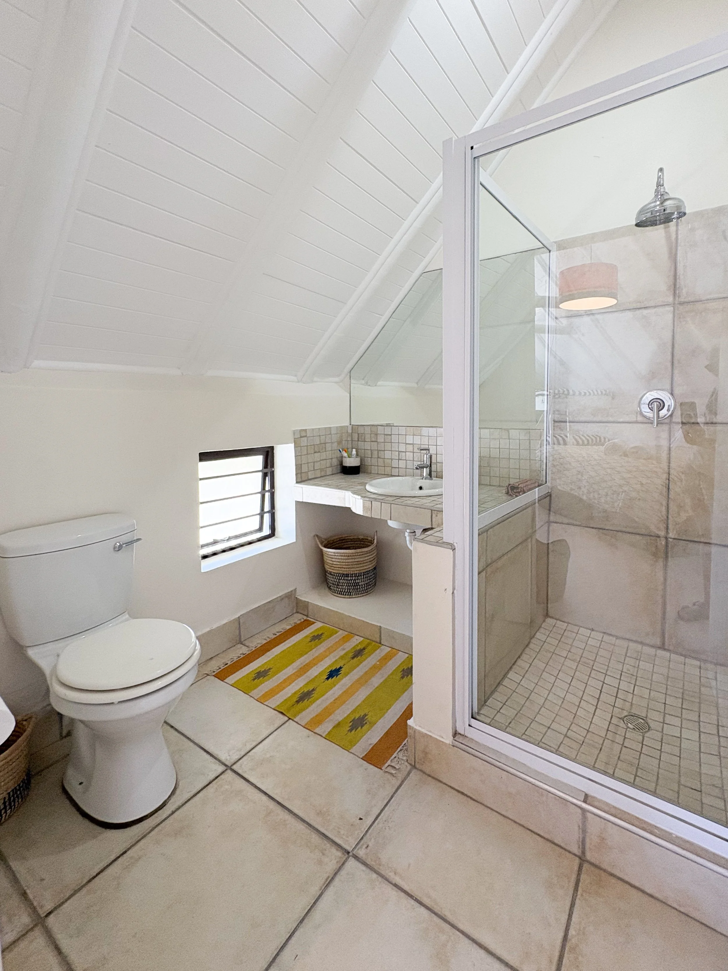 En-suite bathroom with glass shower and vaulted thatched ceiling