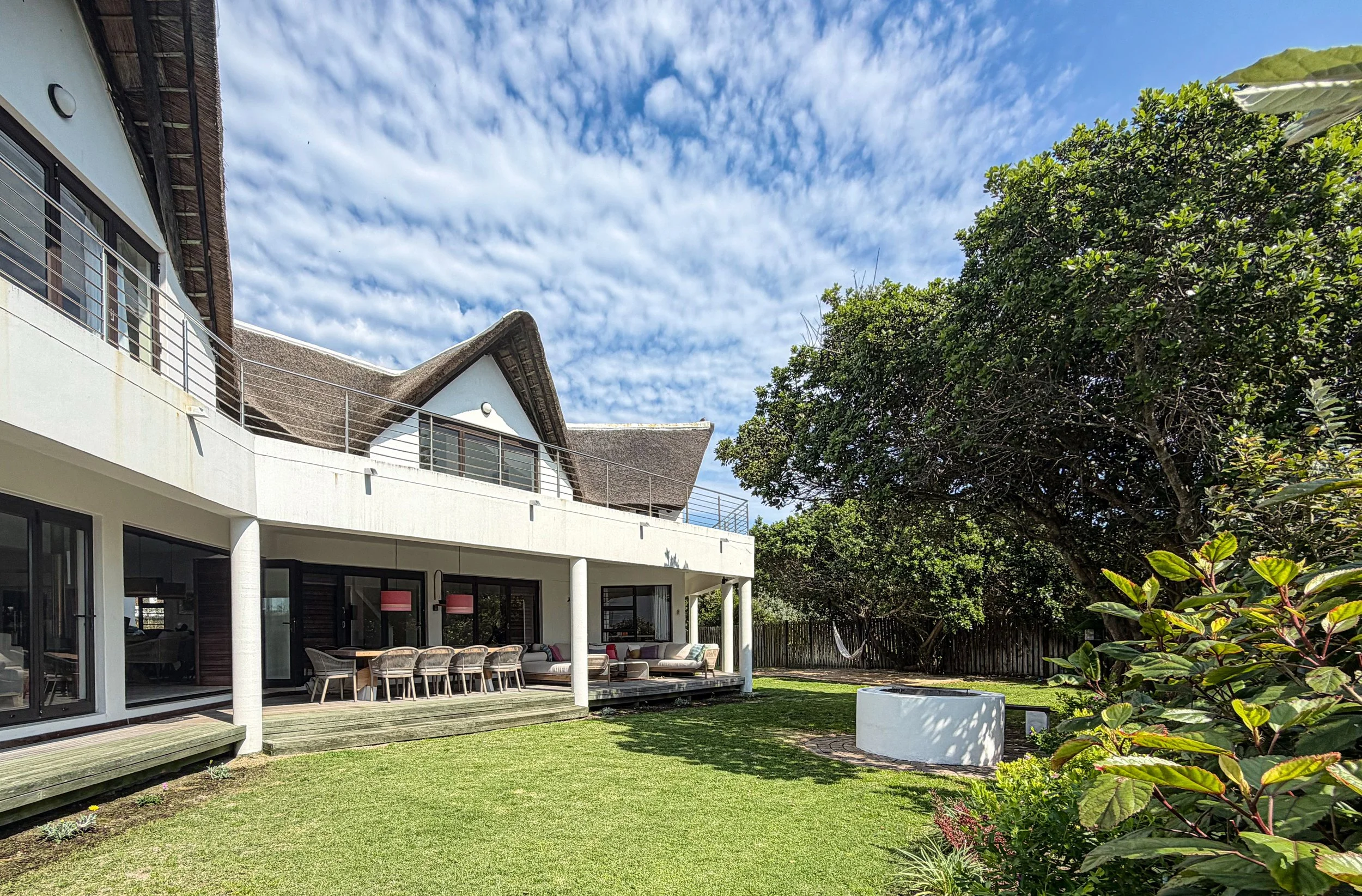 Garden view of St Francis Beach House with hammock, fire pit, and covered patio