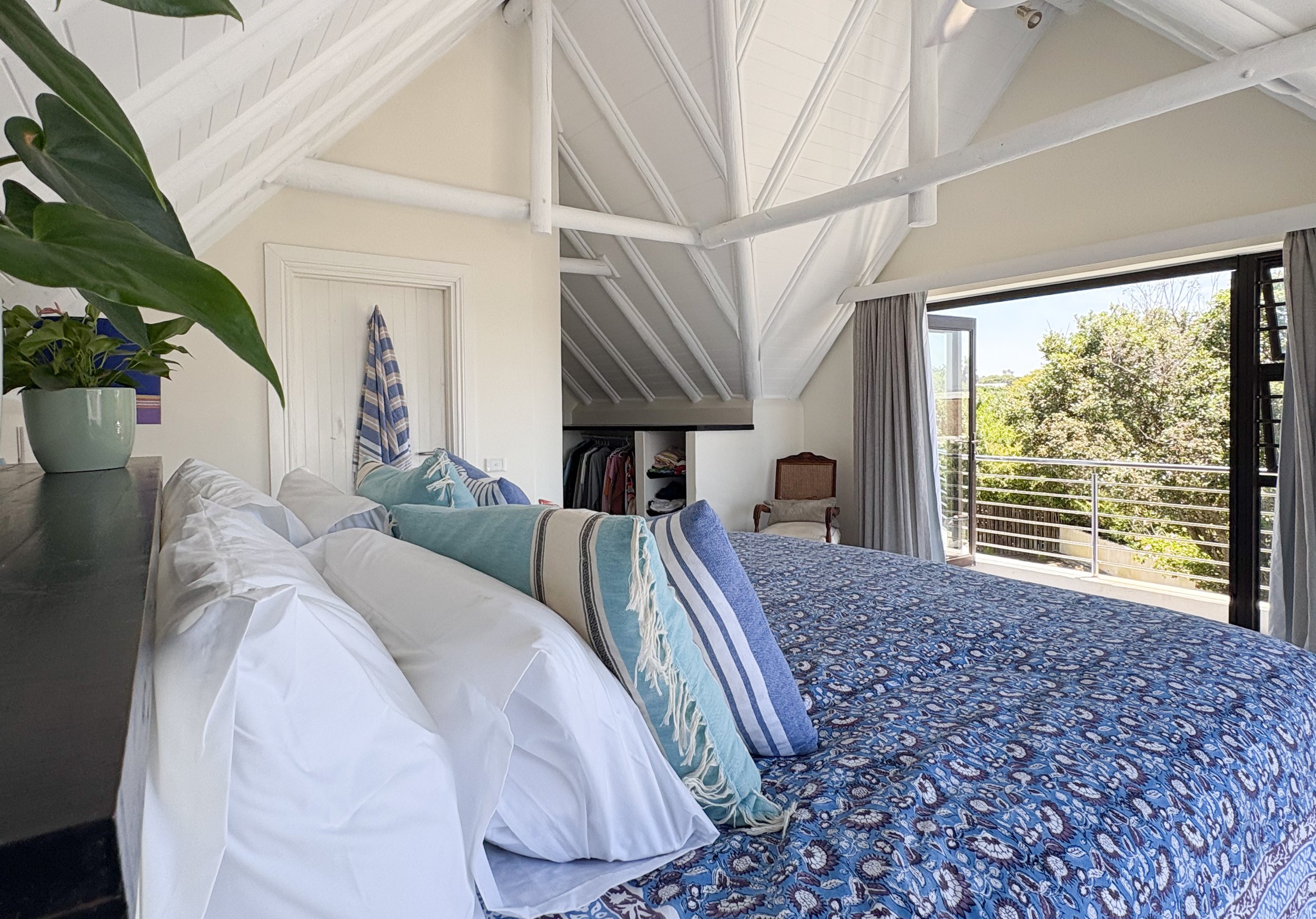 King bed with blue patterned linen and sea view through the open balcony door