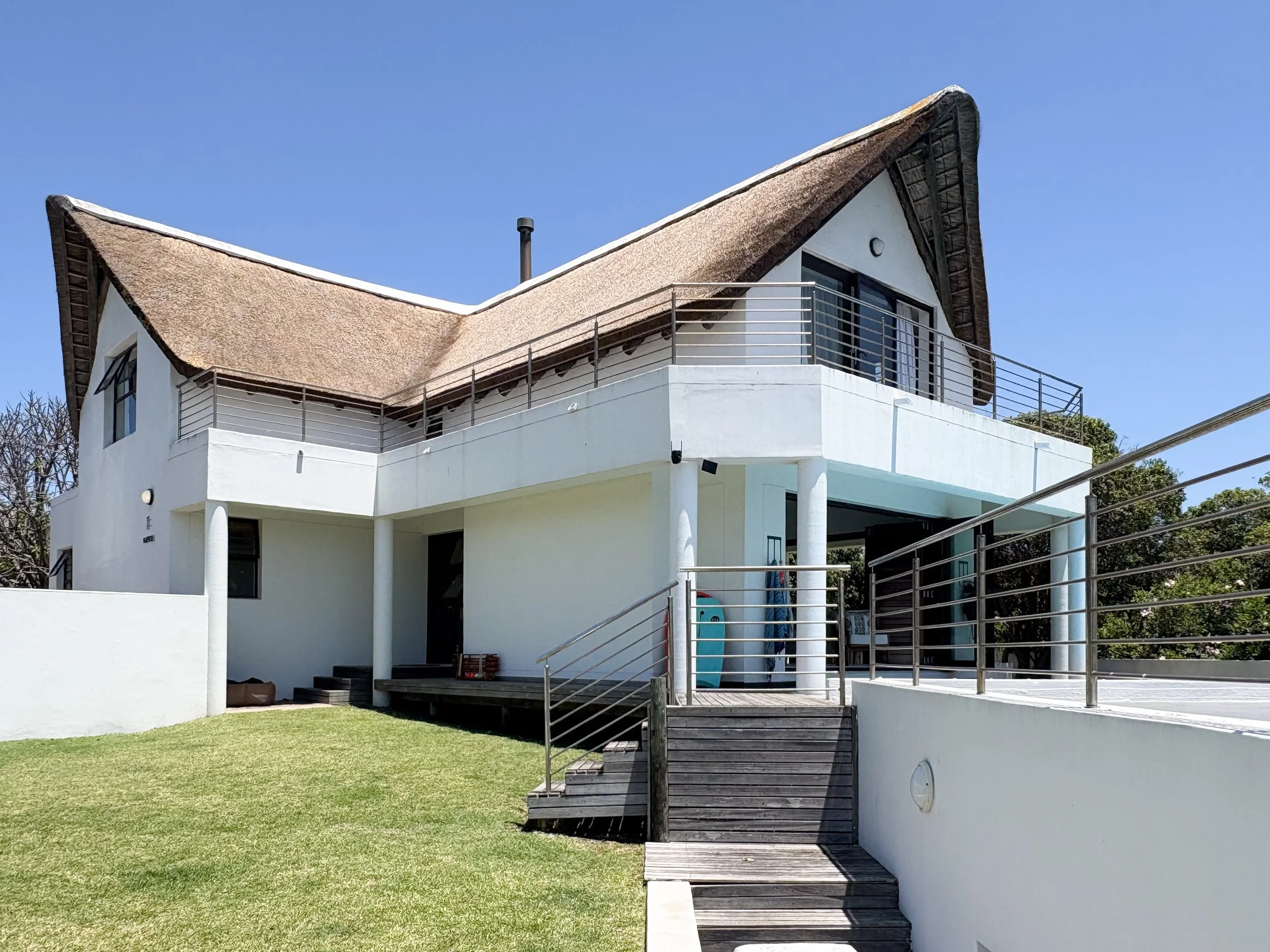 Full exterior view of the house from the garden, with lawn and steps
