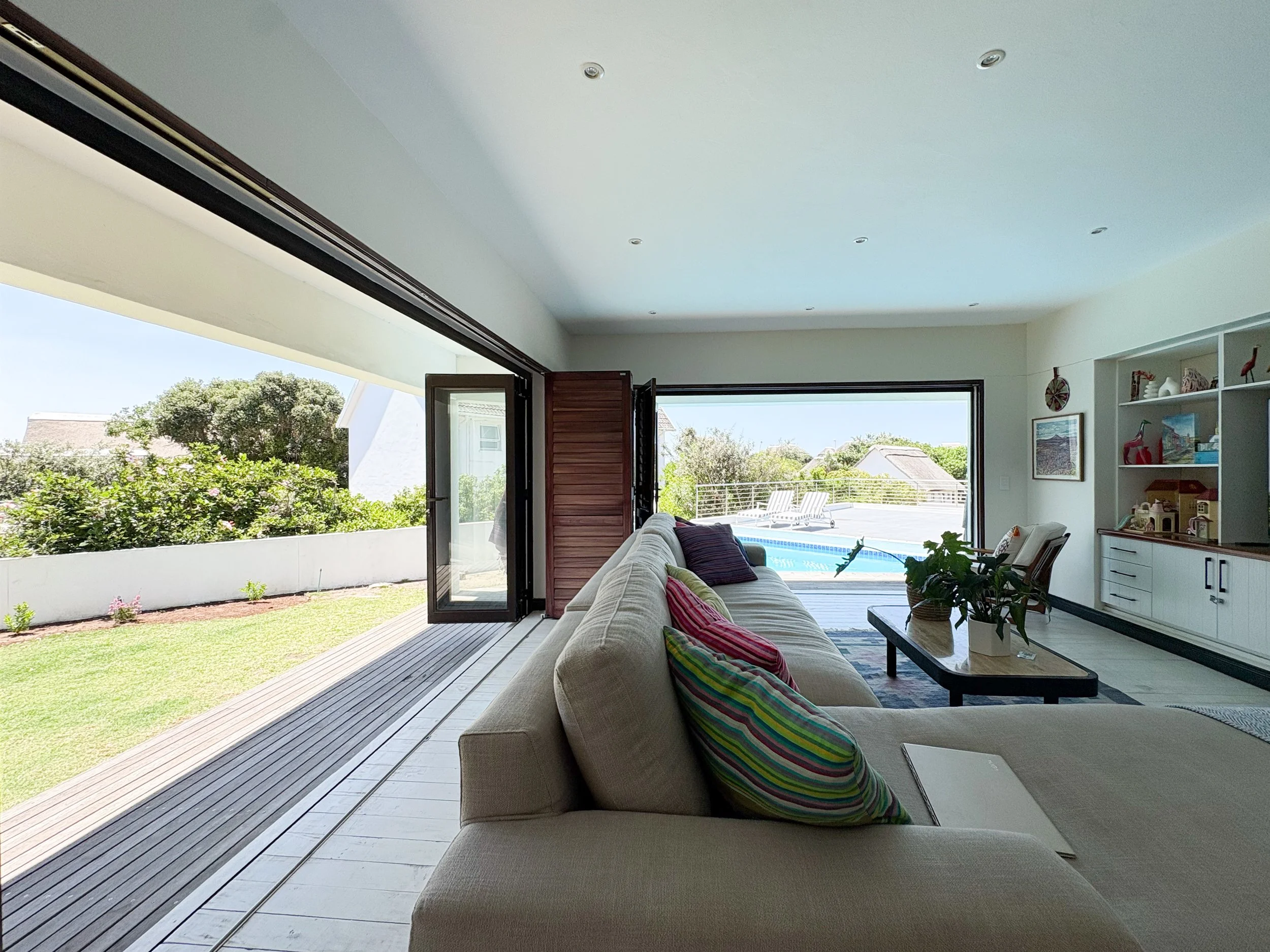 Lounge sofa with garden and pool visible through open folding doors