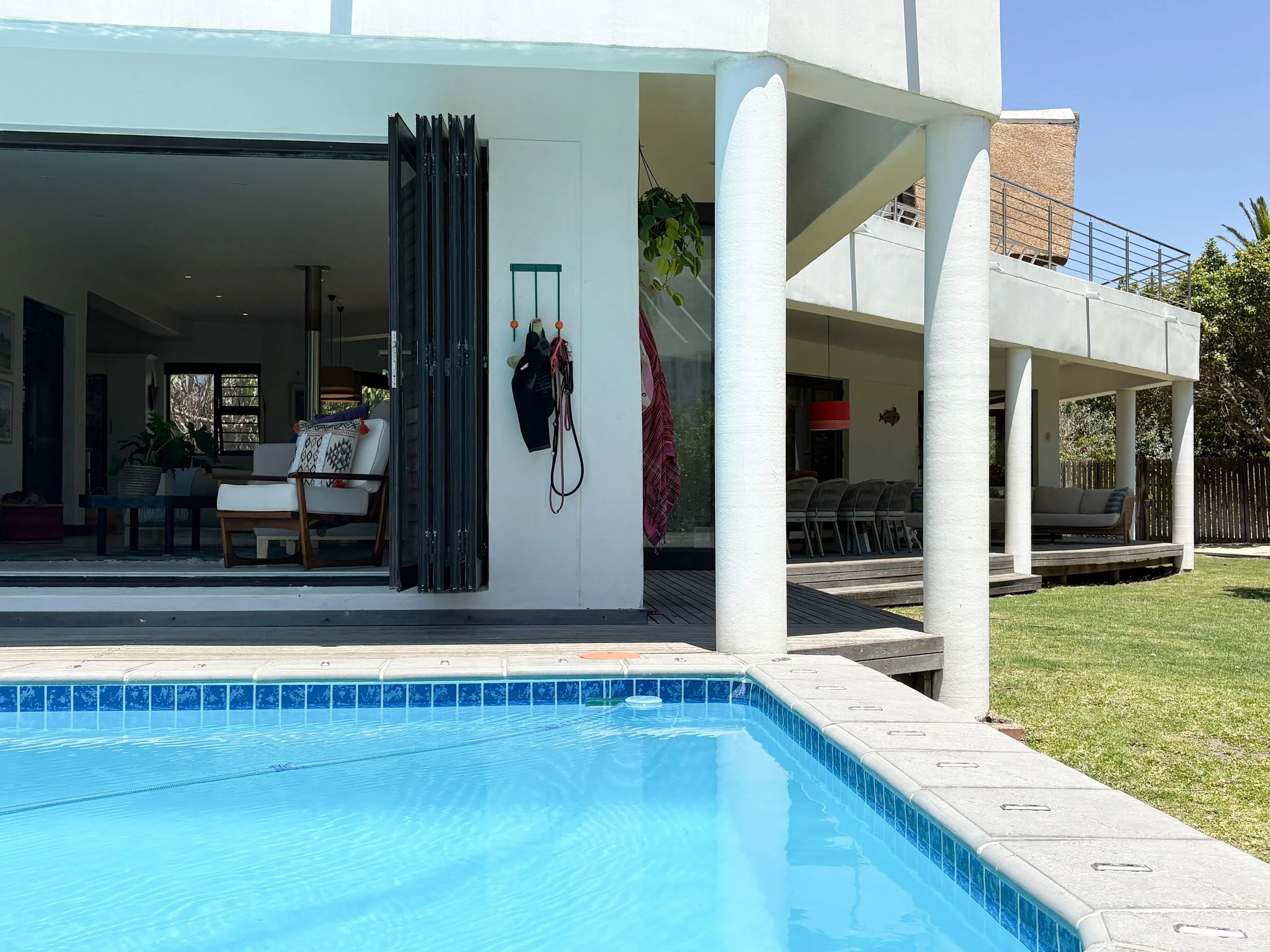 Pool alongside the open-plan lounge, folding doors leading indoors