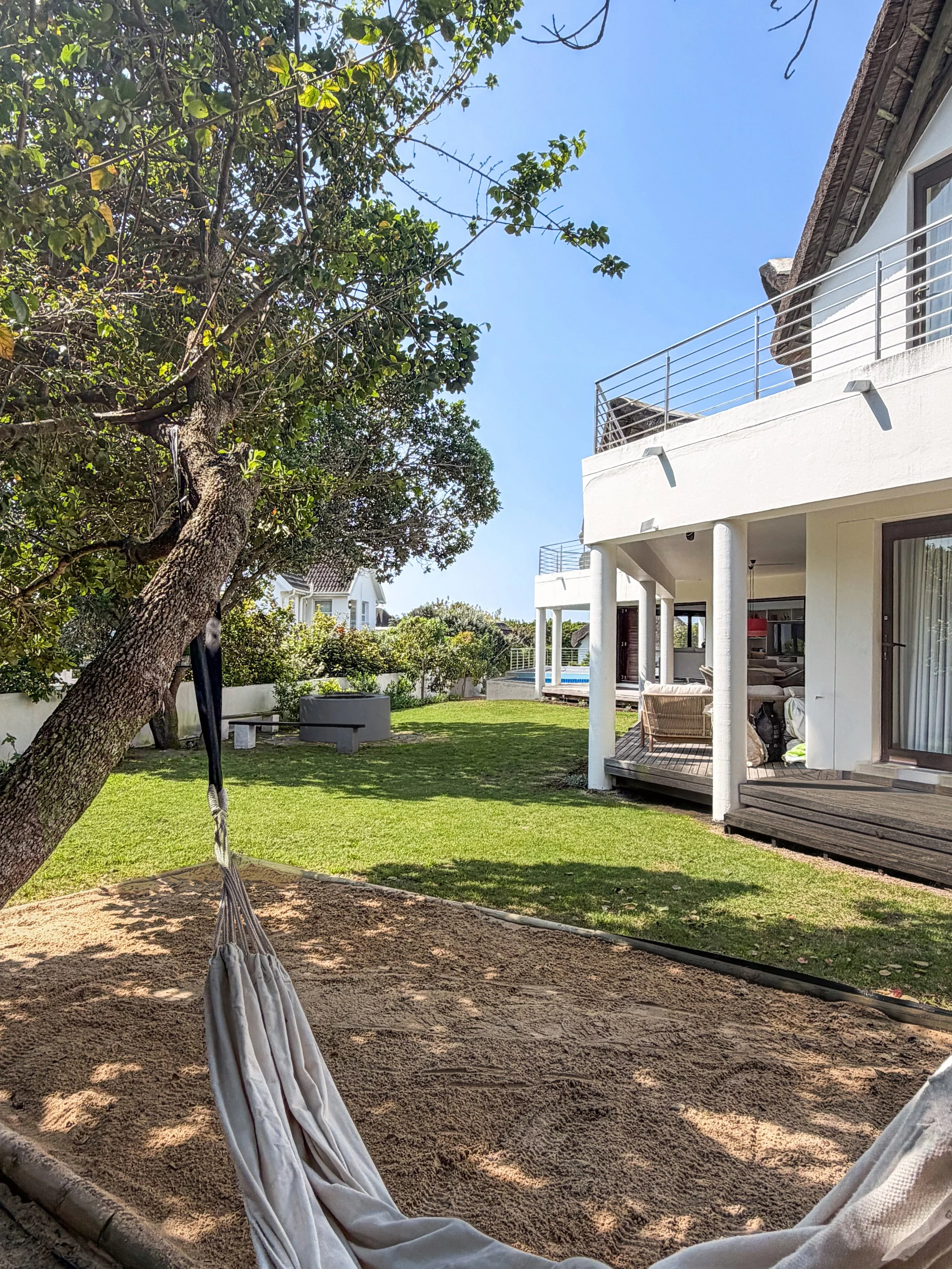 Hammock in the garden at St Francis Beach House, house and fire pit beyond