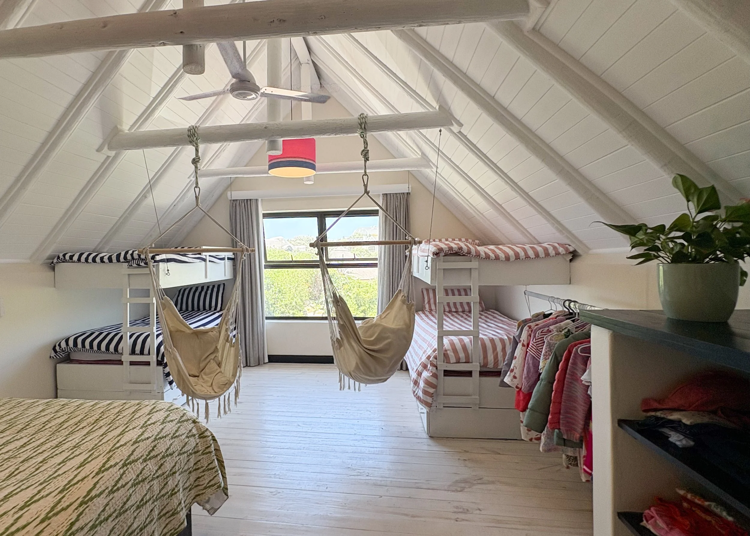 Twin bunk beds either side of a window, each with a hammock chair