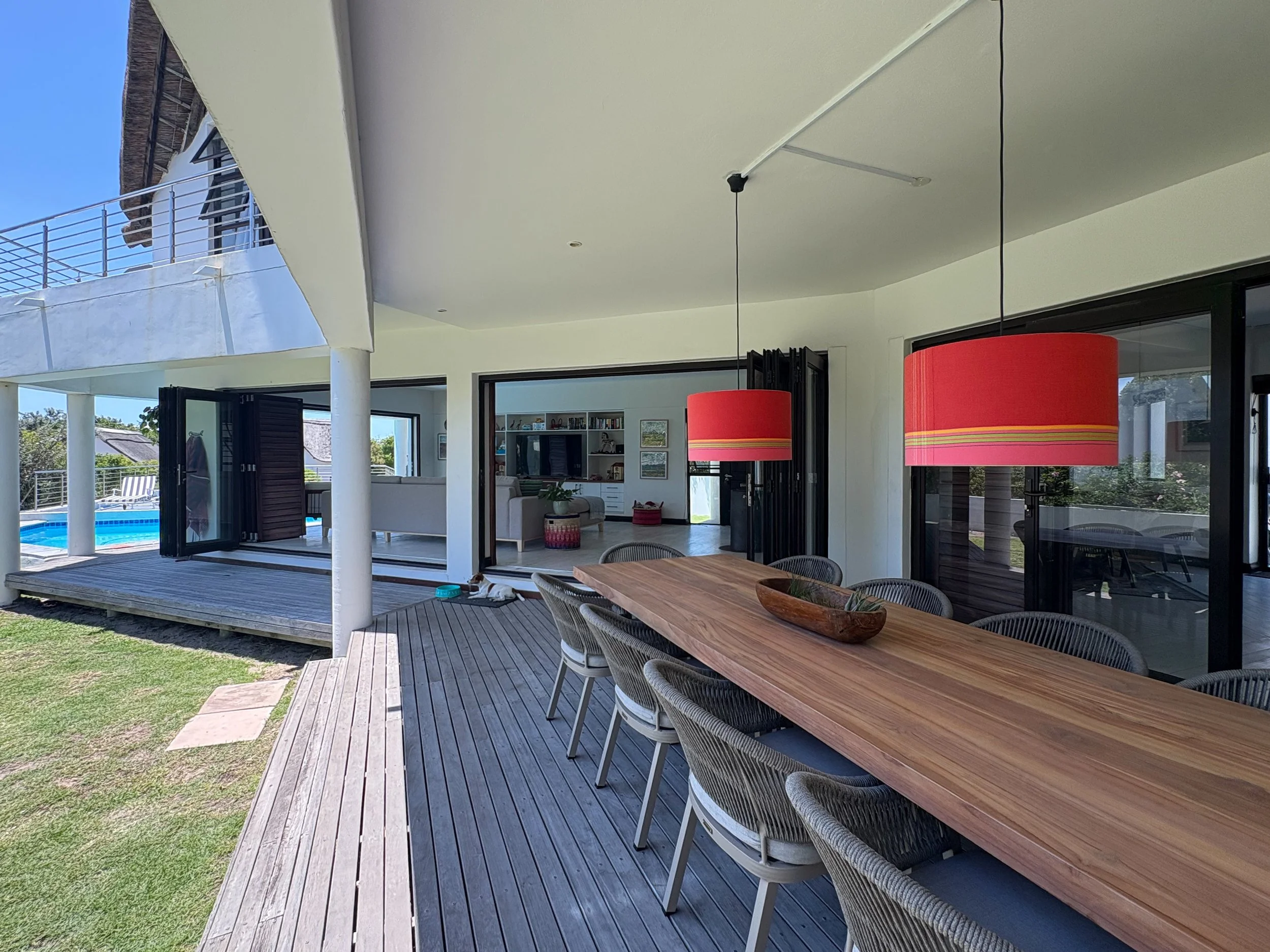 Patio dining table set for a large group beneath red pendant lights