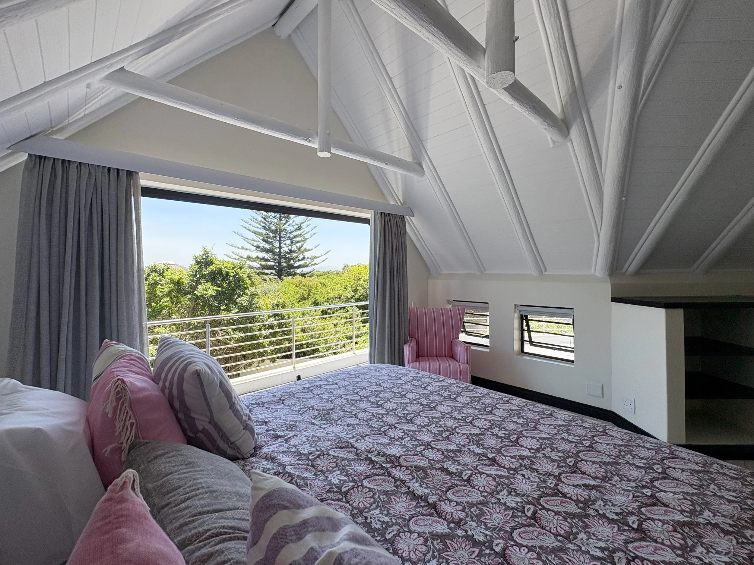 King bed under vaulted thatched ceiling with balcony access